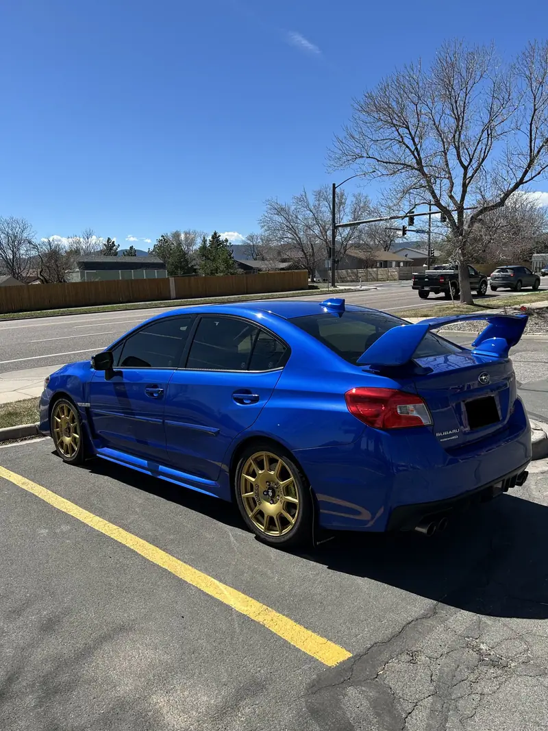 Blue Subaru WRX STI with gold wheels after paint correction and ceramic coating